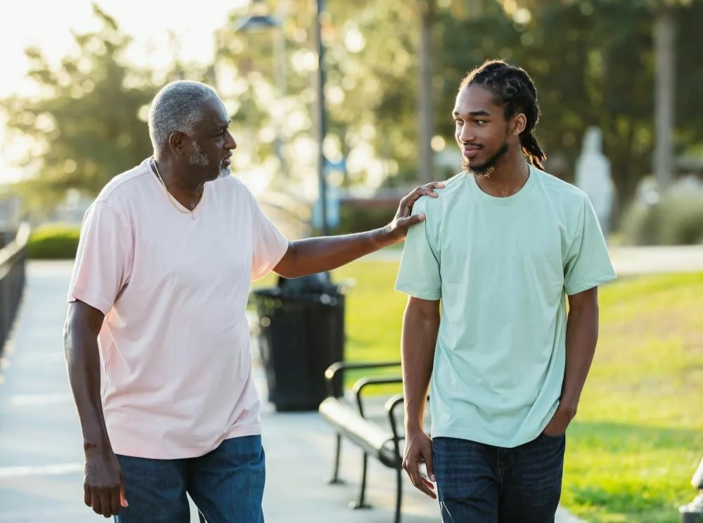 Older man and younger man talking while on a walk