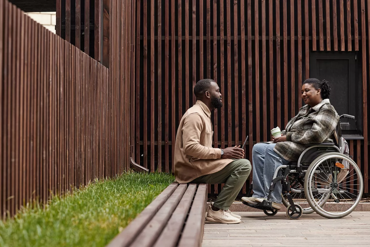 Mujer en silla de ruedas y hombre sentado conversando