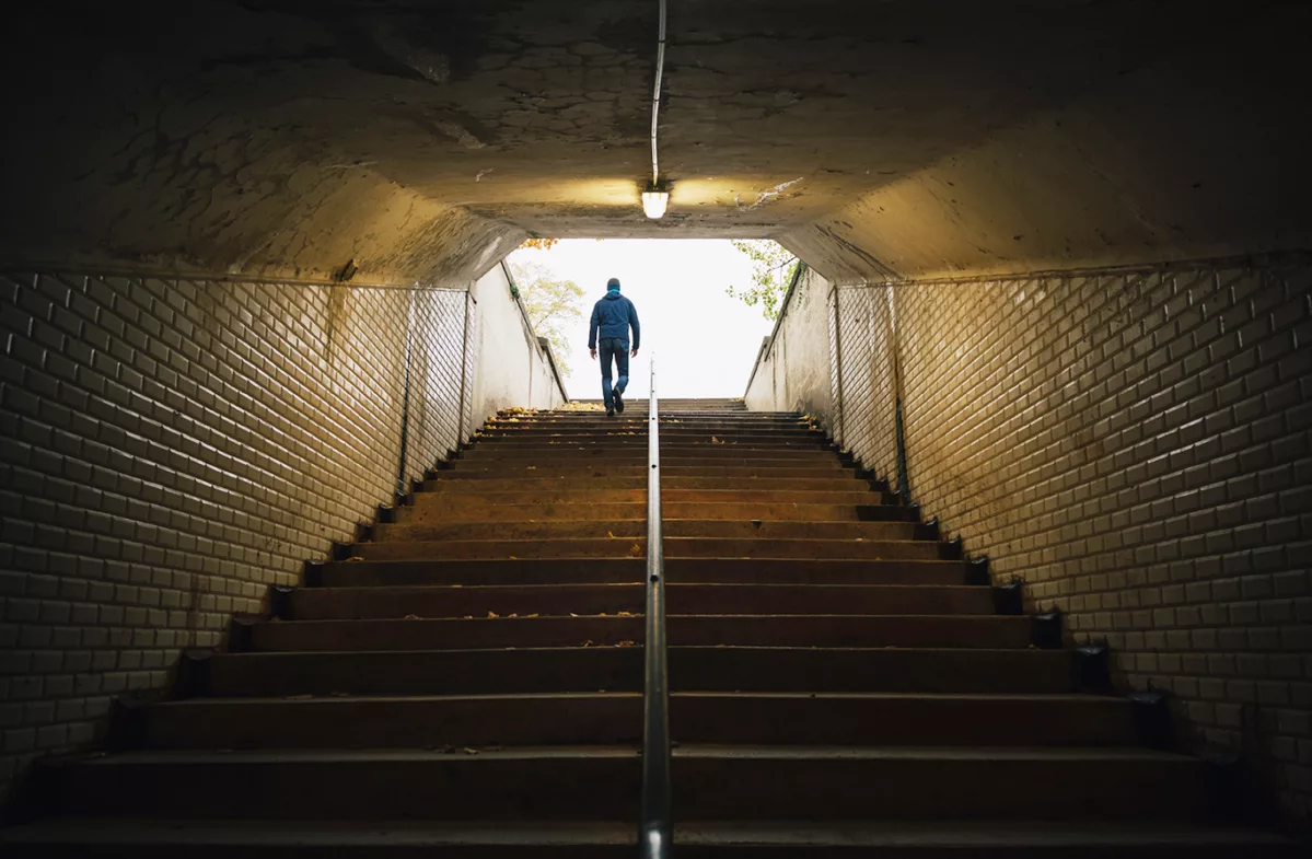 Person climbing up a set of steps from a tunnel