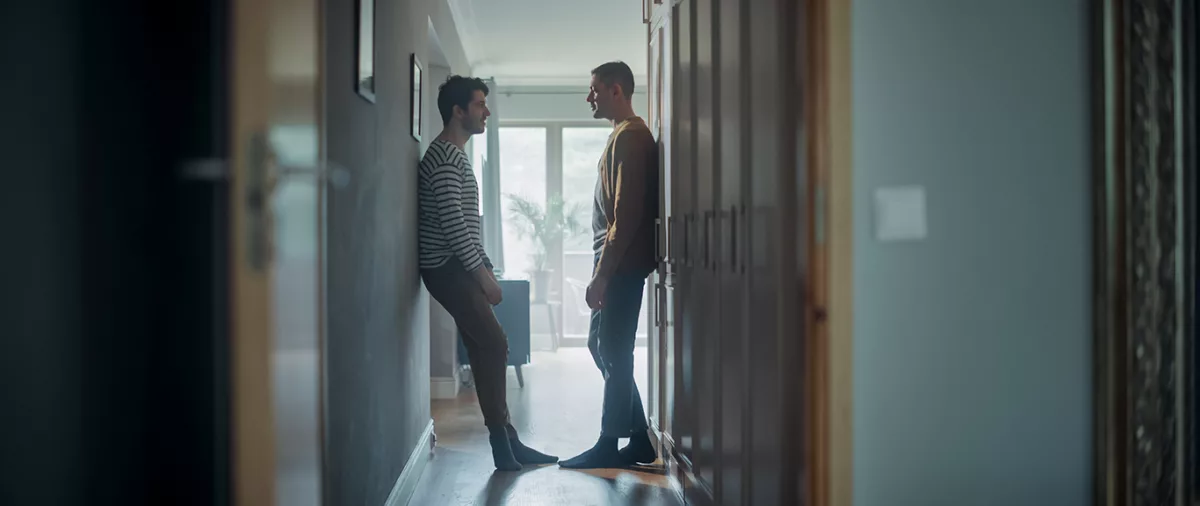 Two men looking at each other and talking in a hallway