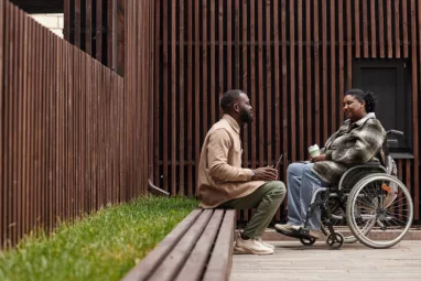 Mujer en silla de ruedas y hombre sentado conversando