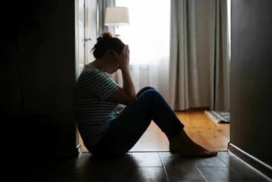 Woman crouched down on the floor with her hands in her palms